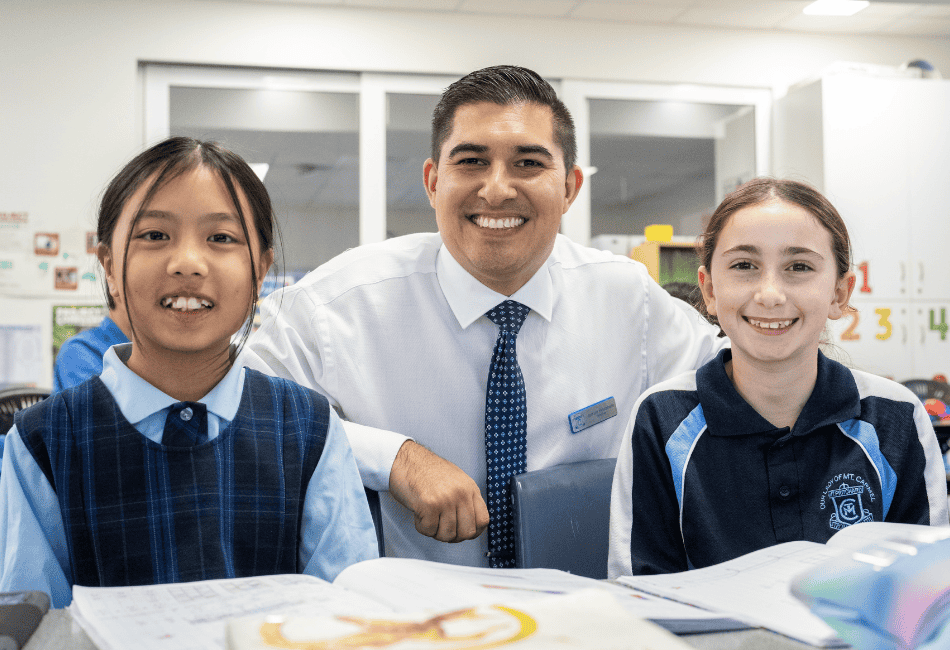 Two Our Lady of Mt Carmel School students and their teacher in front of books